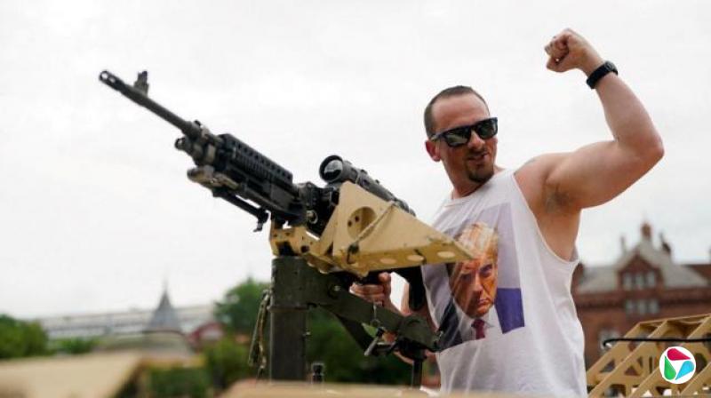 A Trump supporter wearing a t-shirt with the mugshot of U.S. President Donald Trump poses handling a weapon exhibited during the US Army's 250th Anniversary festival on the National Mall on the day of a military parade to commemorate it, in Washington, D.C., U.S., June 14, 2025.