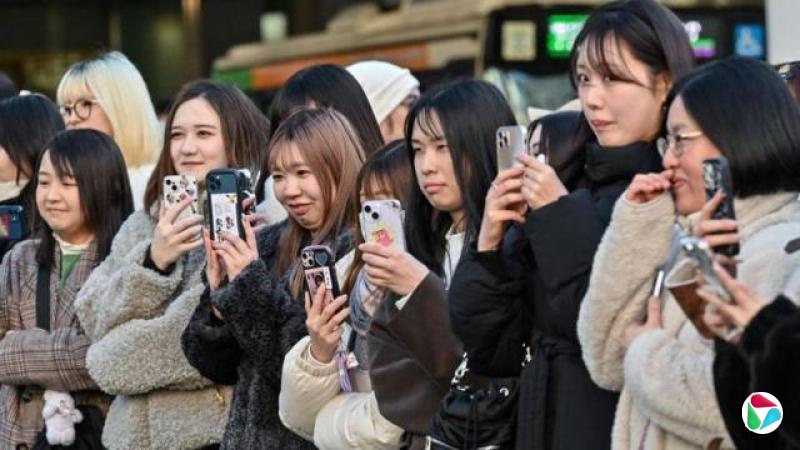 一群日本女性举起手机记录和拍摄眼前的场景