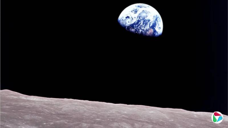 地球的四分之三视图,看起来像一颗带有白色漩涡的蓝色大理石,高耸于月球景观之上。