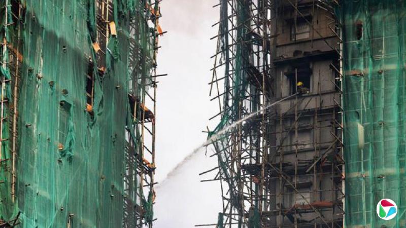 2025年11月27日,香港大埔区宏福苑,一名消防员正用水枪扑灭仍在燃烧的住宅大楼。