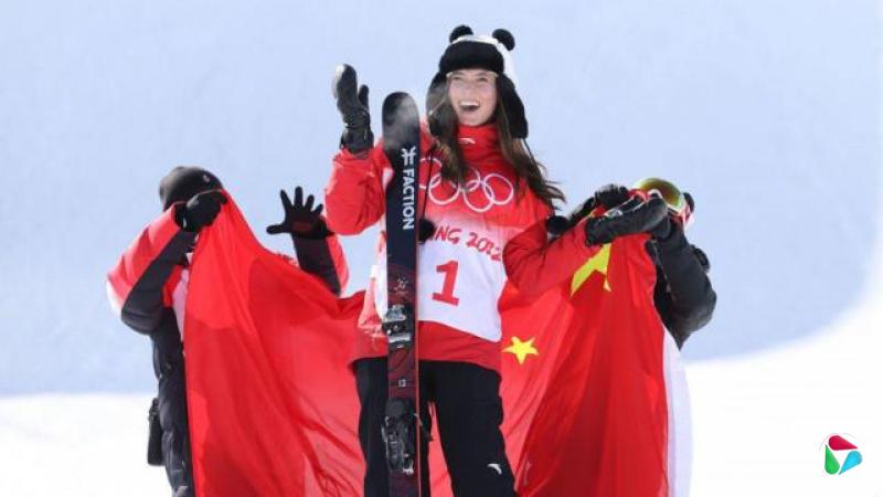2022年北京冬奥会上,谷爱凌头戴熊猫款式的毡帽,团队人员在身后将中国五星红旗递给她