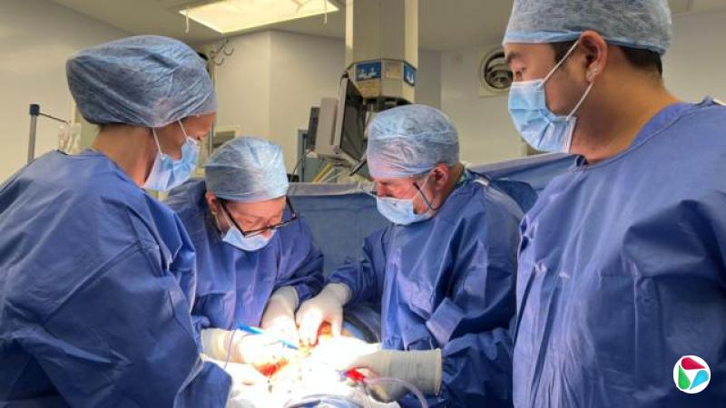 四名身穿蓝色手术服、戴着口罩的外科医生在伦敦一家医院剖腹产手术接生雨果。