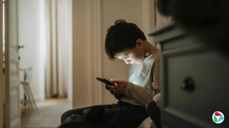 一个男孩低头盯着手机荧幕看
