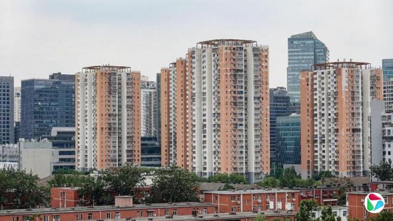在北京,几栋橙白相间的高层公寓大楼矗立在现代高层建筑群前。