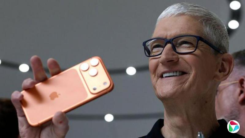 库克在苹果总部一场活动中举起一部iPhone 17 Pro手机
