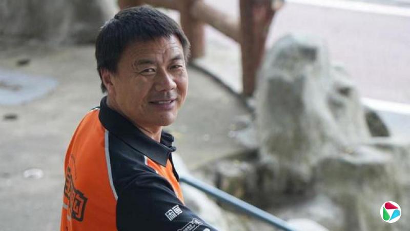 身穿橙色Polo恤的王计兵面带笑容望向镜头。