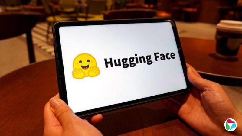 Hugging Face标志显示于平板电脑萤幕上。该标志是一个黄色笑脸表情符号,双手向前张开。