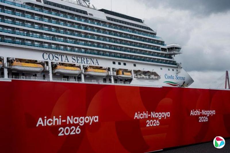 意大利邮轮Costa Serena停泊于阴云密布的天空下,前景可见写有“Aichi-Nagoya 2026”的大型标志。