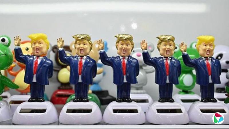 浙江义乌某展场内,五个以唐纳德·特朗普为原型、带有夸张漫画风格的人偶整齐排列在附有小型太阳能板的白色底座上。每个人偶都身穿蓝色西装、系着红色领带,并举起一只手臂。(资料图片)
