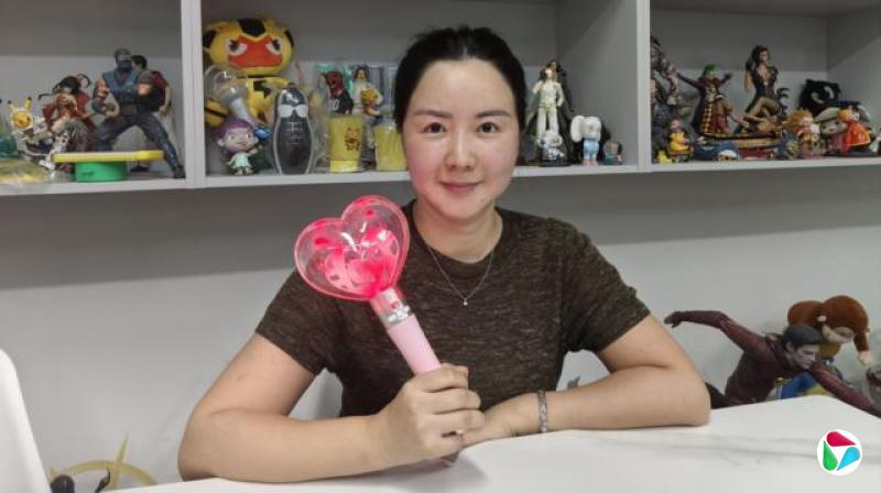 来自新美汇未来销售团队的旺静举起玩具。她坐在摆满其他玩具的货架前。